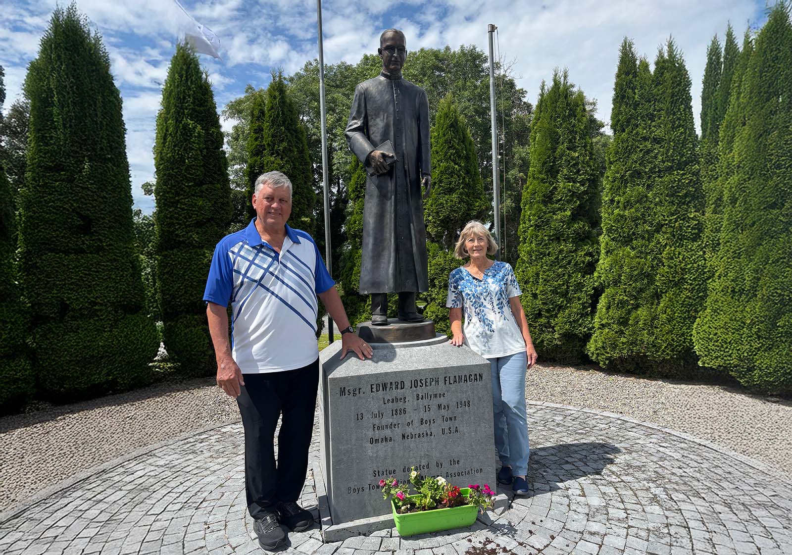 Jack Flanagan and his wife Cindy posing next to the Father Flanagan statue in the Father Flanagan Visitor Centre gardens.