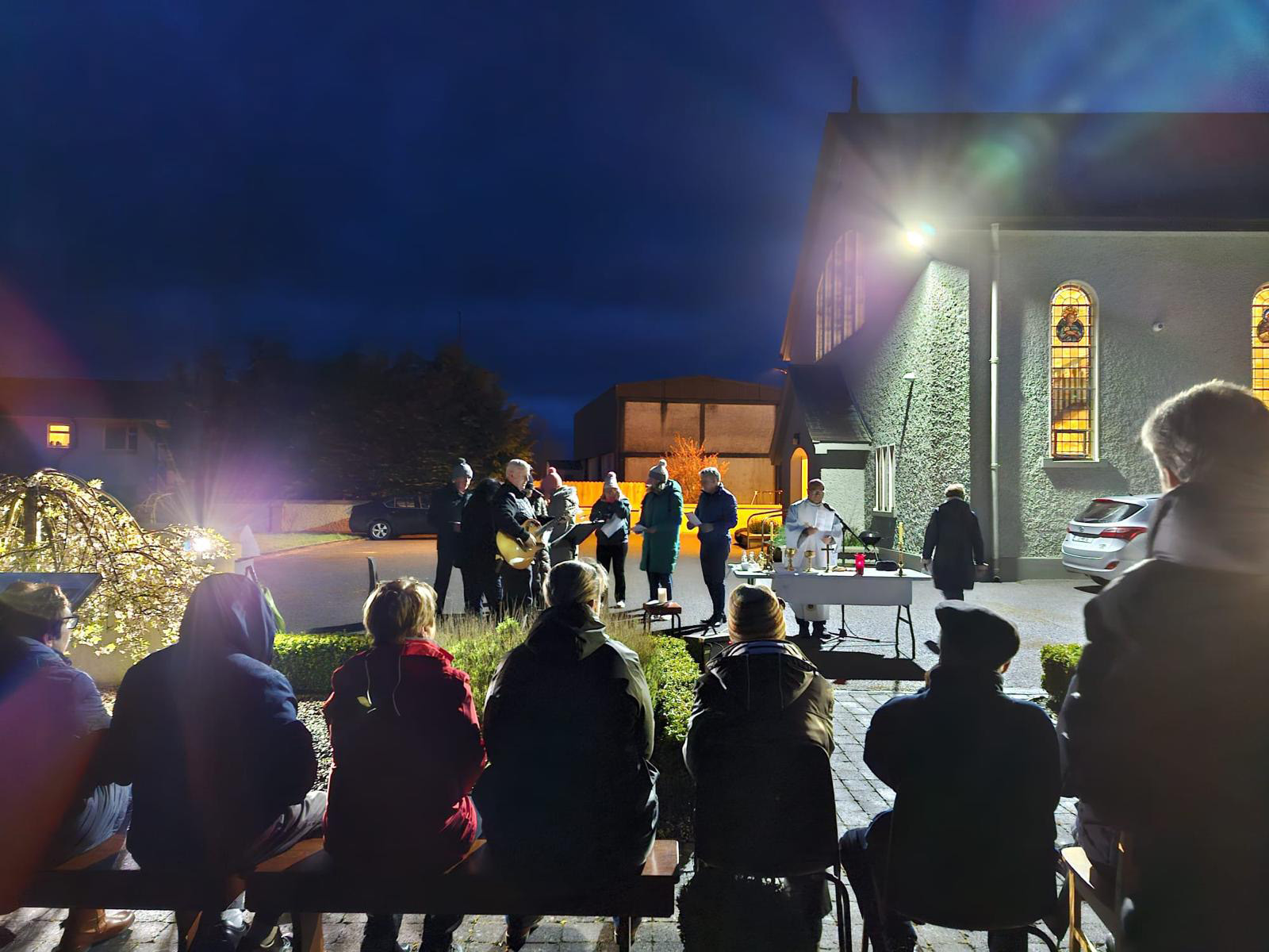 Group of people celebrating Easter Dawn Mass outside church. Alternative view.